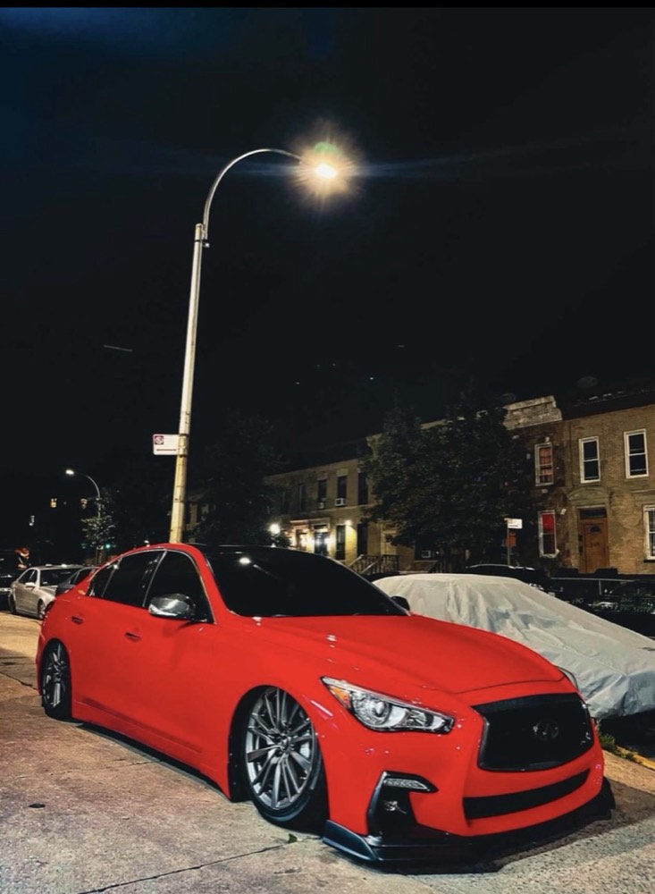 Red Infiniti Q50 with a full color change wrap and front splitter, parked at night in New York City
