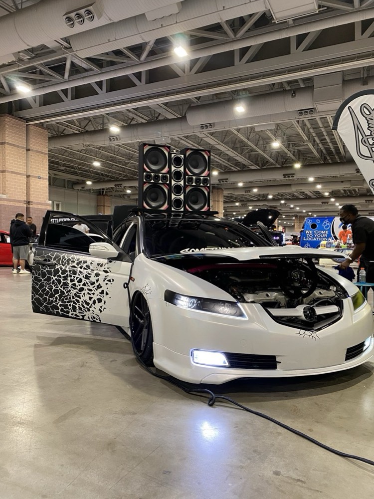 Show car with a custom printed wrap and doors open at an indoor car show